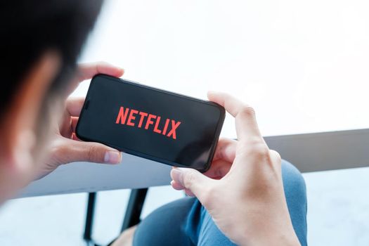 CHIANG MAI, THAILAND,  JAN 17 2021: man hand holding Smart Phone with Netflix logo on Apple iPhone Xs. Netflix is a global provider of streaming movies and TV series.
