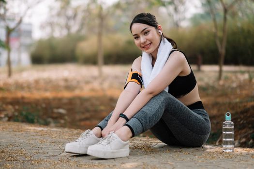 Athletic asian woman resting after a hard training in the mountains at sunset. Sport tight clothes.