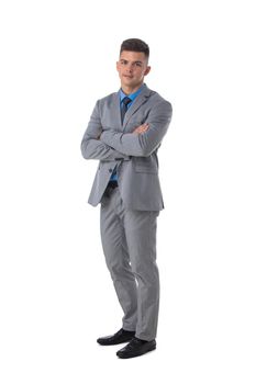 Full length portrait of a young business man in gray suit standing with arms folded isolated on white background