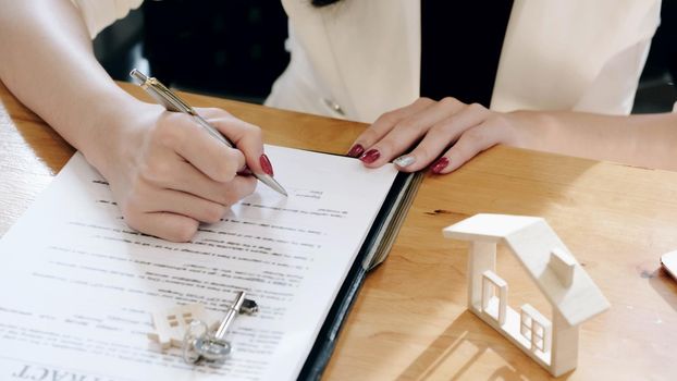 Real estate agents and client to agree buy a home and sign documents contract house with customer.
