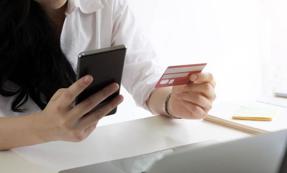 Online payment,woman's hands holding smartphone and using credit card for online shopping.
