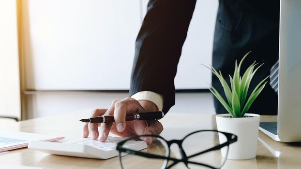 Close up Business woman using calculator and laptop for do math finance on wooden desk in office and business working background, tax, accounting, statistics and analytic research concept
