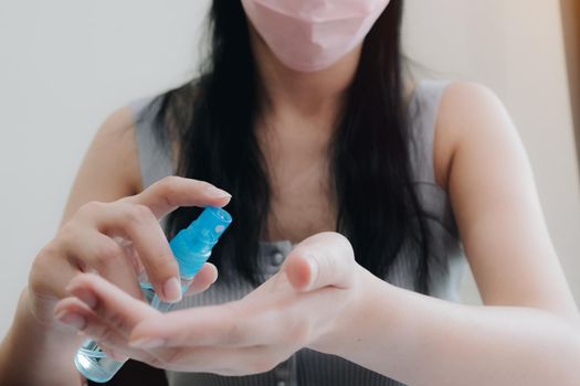 Coronavirus. Business woman working from home wearing protective mask. Business woman in quarantine for coronavirus wearing protective mask. Working from home. Cleaning her hands with Alcohol spray.
