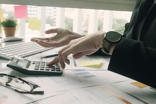 Business woman using calculator and laptop for do math finance on wooden desk in office and business working background, tax, accounting, statistics and analytic research concept
