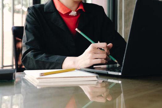 Close up of businessman or accountant hand holding pencil working on calculator to calculate financial data report, accountancy document and laptop computer at office, business concept
