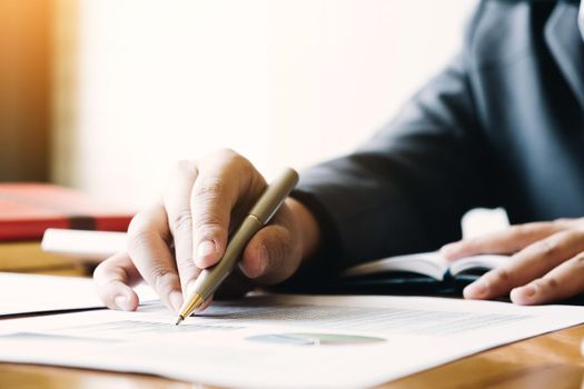 Close up of businessman or accountant hand holding pencil working on calculator to calculate financial data report, accountancy document and laptop computer at office, business concept
