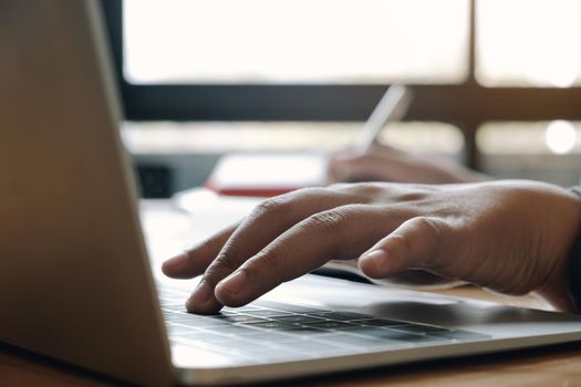 Close up of businessman or accountant hand holding pen working on laptop computer for calculate business data, accountancy document and calculator at office, business concept
