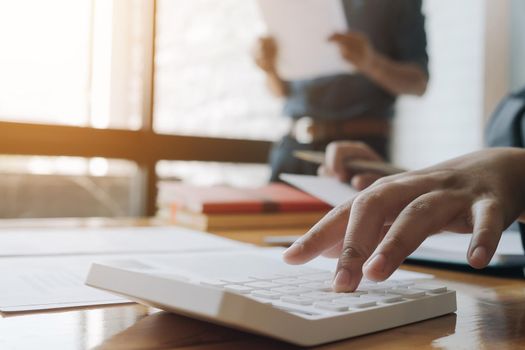 Business woman using calculator for do math finance on wooden desk in office and business working background, tax, accounting, statistics and analytic research concept
