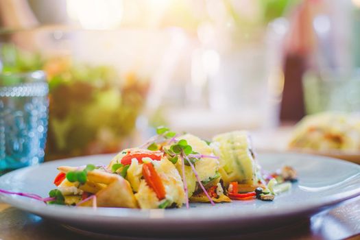 Close up of egg omelet with fresh vegetables. Placed on white ceramic plate.
