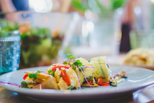 Close up of egg omelet with fresh vegetables. Placed on white ceramic plate.