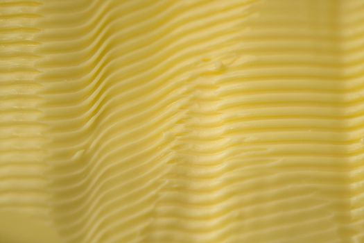 Full frame background texture of ripples in yellow margarine. Possible healthier food choice to traditional butter. Manufactured spreadable diary.