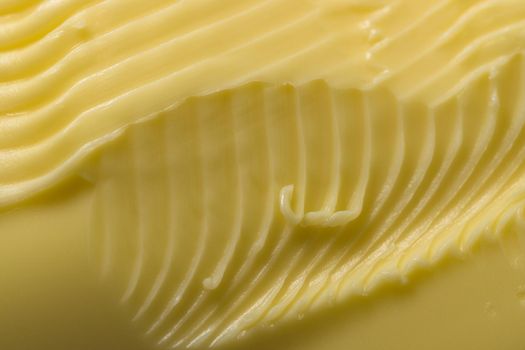 Super close up macro background of intricate grooves and swirls of margarine. Made by a serrated kitchen knife that was swept over the surface.