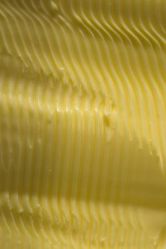 Vertical food texture image. Full frame margarine, textured into wavy ridges using a knife. Commonly found in kitchens as an alternative to butter
