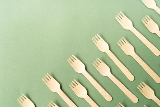Reusable, disposable and recycling concept. Disposable wooden forks top view on green background with copy space