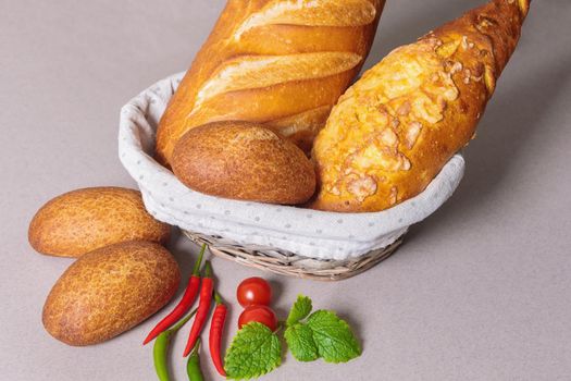 Fresh bread in a basket on the table with red peppers and tomatoes. Close-up