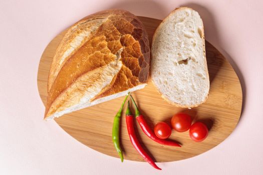 Sliced pieces of white bread with red peppers and tomatoes on a cutting board. Light background