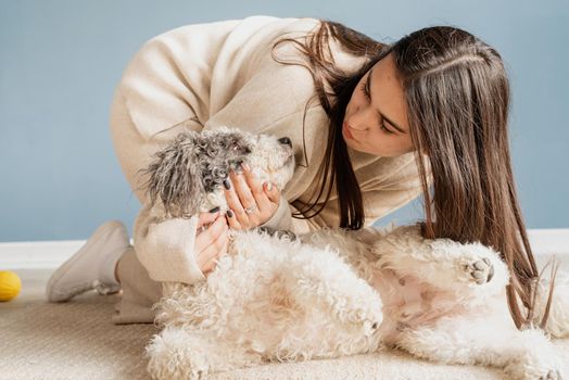 Beautiful brunette woman with playful mixed breed dog, embracing and having fun at home