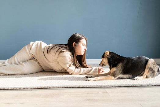 Beautiful brunette woman with playful mixed breed dog, embracing and having fun at home