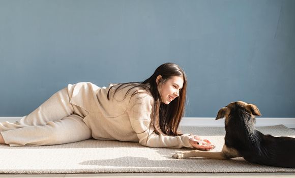 Beautiful brunette woman with playful mixed breed dog, embracing and having fun at home