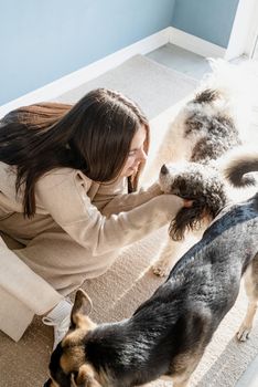 Beautiful brunette woman with playful mixed breed dog, embracing and having fun at home