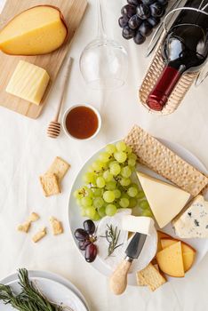 Cheese plate: Maasdam, Camembert cheese, blue cheese, bread , grapes, rosemary, wine, honey, grapes on table