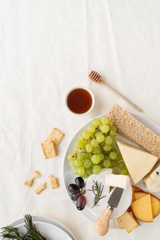 Cheese plate: Maasdam, Camembert cheese, blue cheese, bread, grapes, rosemary, honey, grapes on table