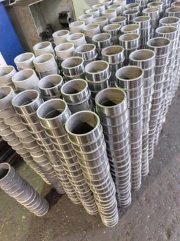 stacks of many siny steel sleeve parts after cnc turning operations on factory floor