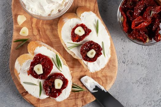 Homemade sandwiches with cream cheese and sun-dried tomatoes on a wooden board of olive - delicious healthy breakfast, italian cuisine, flat lay.