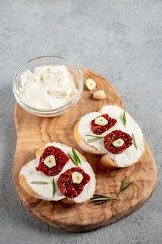 Homemade sandwiches with cream cheese and sun-dried tomatoes on a wooden board of olive - delicious healthy breakfast, italian cuisine, vertical image, copy space.