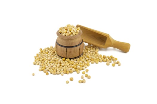 Dried peas spilling from a wooden barrel and wooden scoop isolated on a white background