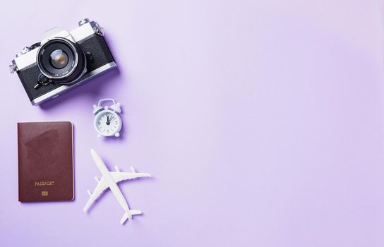 Top view flat lay mockup of retro camera films, airplane, passport travel accessories isolated on a purple background with copy space, Business trip, and vacation summer travel concept