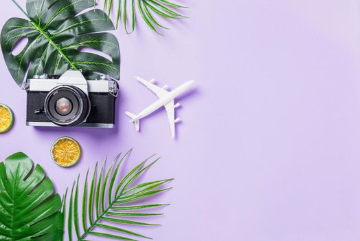 Top view flat lay mockup of retro camera films, airplane, leaves and traveler accessories isolated on a purple background with copy space, Business trip, and vacation summer travel concept
