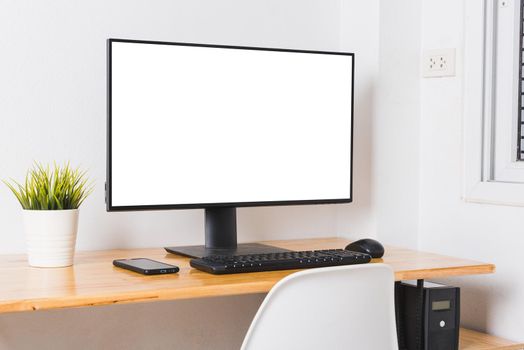 Computer monitor with white blank screen on the business desk with wireless mouse, keyboard at home office over white wall background, Photo of equipment contemporary workspace