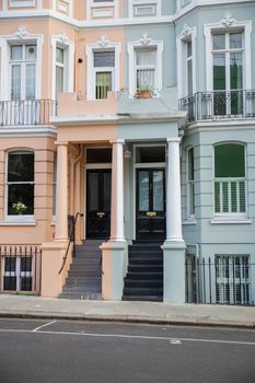 British duplex house with light colors and columns outside the doors. Beautiful English houses with pastel colors and Victorian architecture. Peaceful London neighborhood