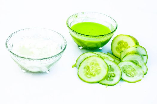 Cucumber face pack isolated on white i.e. Cucumber pulp well mixed with dahi or yogurt in a glass bowl and entire raw ingredients present on the surface.Used to cure acne prone skin.