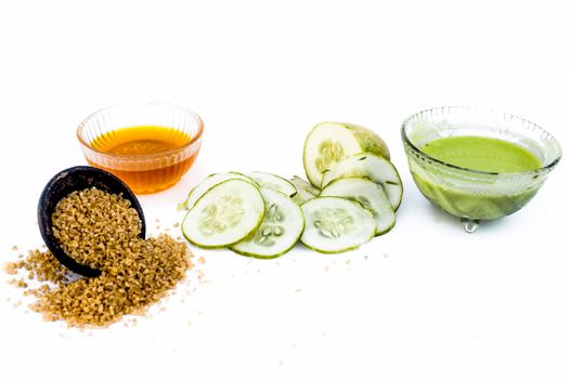 Cucumber face pack isolated on white i.e. Cucumber slices or cucumber pulp well mixed with turmeric powder and some lemon juice in a bowl and entire raw ingredients present on the surface.