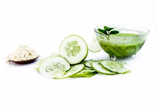 Cucumber face pack isolated on white i.e. Cucumber juice well mixed with gram flour in a glass bowl and all the raw ingredients present on the surface.Used for instant glow.