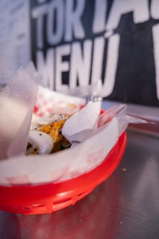 Fries and onions on red plastic basket with the words menu and tortas behind it. Fried snacks on paper with chessboard texture and white words as background. Traditional Mexican cuisine