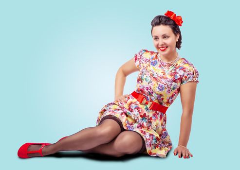 young beautiful woman posing while sitting on the floor in studio. pinup style