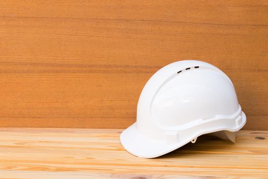 white safety helmet plastic construction of engineering on wood floor table background with copy space add text