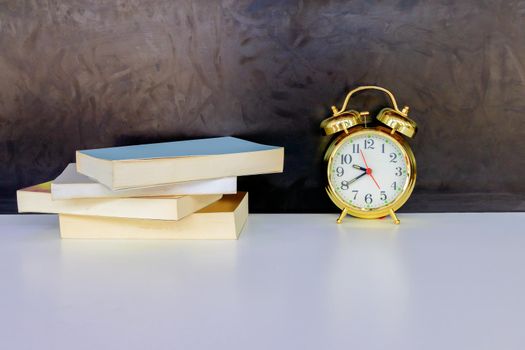 alarm clock old vintage gold and book over white on black background. with copy space add text