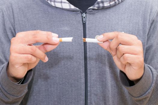 male young holding broken cigarette in hands. health care concept stop quitting smoking.