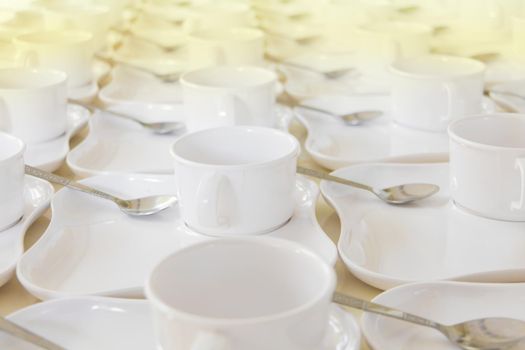 white coffee cup row with saucer and spoon on table