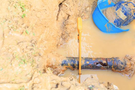 repair broken pipe in hole with plumbing water flow underground outdoor and sunlight with copy space add text