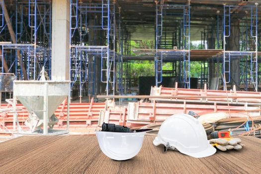 two white safety helmet and leather glove Measuring Tape, roll paper plan blueprint for engineering working interior construction site building on wood floor table with copy space add text. blur background