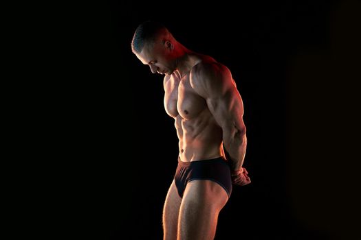 Active lifestyle concept. Professional bodybuilder showing perfect muscular body, lamps illumination on background Sport and fitness concept