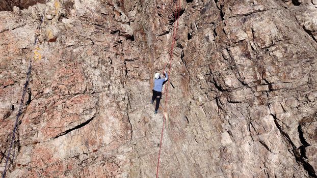 A group of people are engaged in rock climbing. High steep cliff. With the help of a rope, insurance and a partner, climbers climb to the top. Winter time of the year, sometimes there is snow.