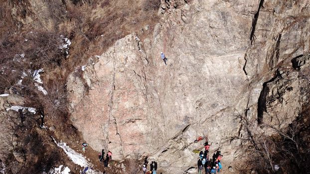 A group of people are engaged in rock climbing. High steep cliff. With the help of a rope, insurance and a partner, climbers climb to the top. Winter time of the year, sometimes there is snow.