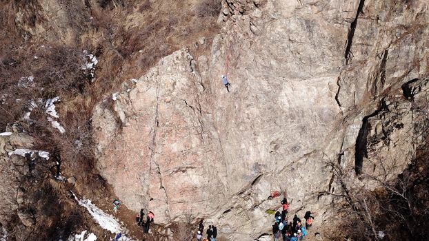 A group of people are engaged in rock climbing. High steep cliff. With the help of a rope, insurance and a partner, climbers climb to the top. Winter time of the year, sometimes there is snow.