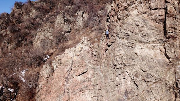 A group of people are engaged in rock climbing. High steep cliff. With the help of a rope, insurance and a partner, climbers climb to the top. Winter time of the year, sometimes there is snow.